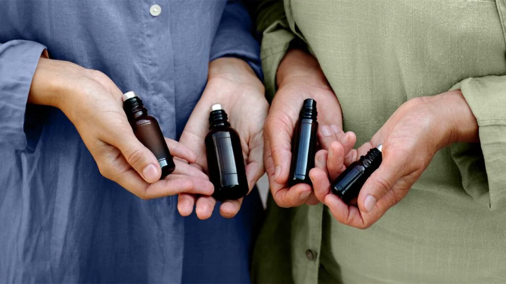 Personne tenant des flacons d'huiles essentielles pour l'aromathérapie