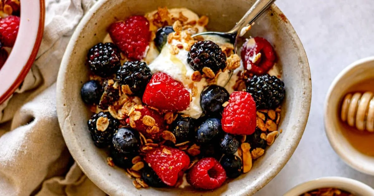 Cuillère de miel ajoutée à un yaourt frais pour préserver les enzymes et nutriments du miel