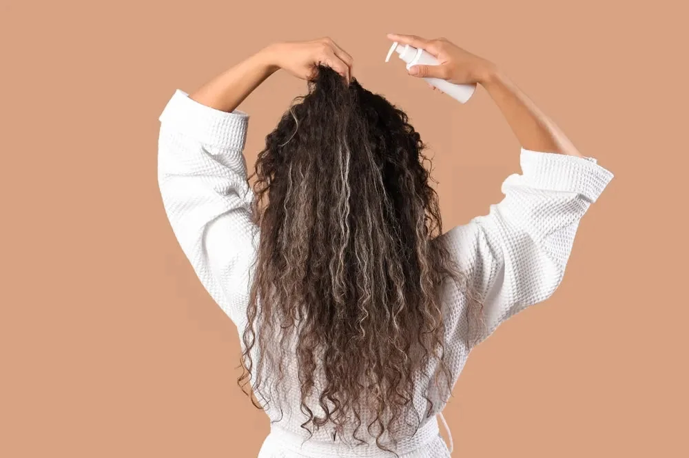 Femme massant son cuir chevelu avec une lotion de rinçage au romarin